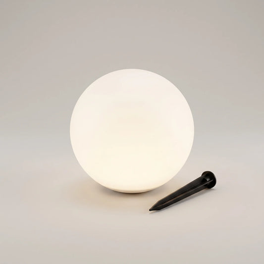 Frosted white globe light beside its black ground stake on a plain background