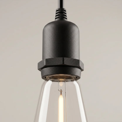 Close-up of one black lamp socket with its ribbed cable grip and the lit filament bulb below