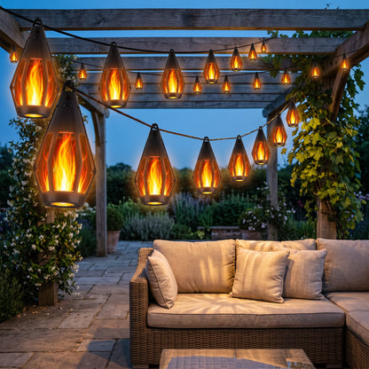 Flame lanterns strung across a garden pergola above patio seating