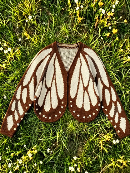 Butterfly wing knit cardigan in cream and brown, laid flat on grass
