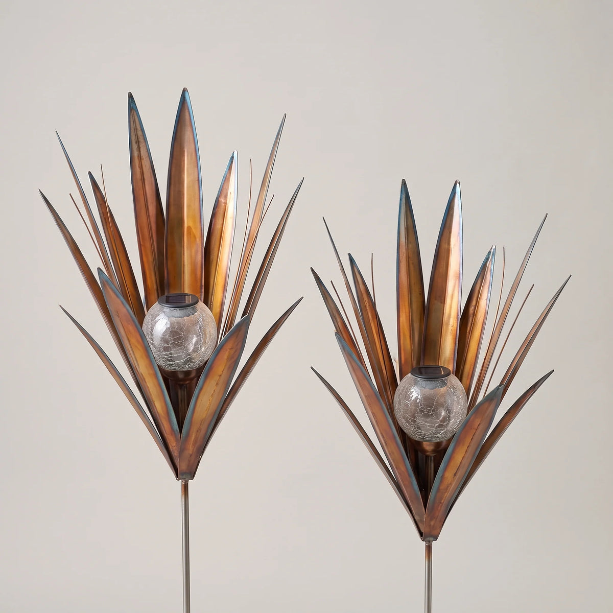 Pair of metal agave solar garden lights, large and small, unlit on a studio backdrop