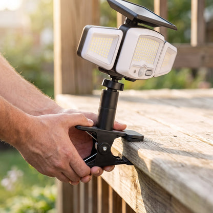 Hands clamping the solar flood light onto a wooden deck rail