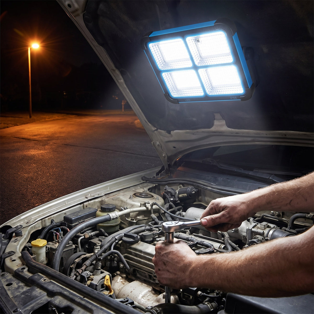 Work light stuck by its magnetic back under a raised car hood, lighting a mechanic's hands