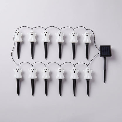 Twelve white ghost stake lights wired to a single solar panel, laid out flat on a pale grey background