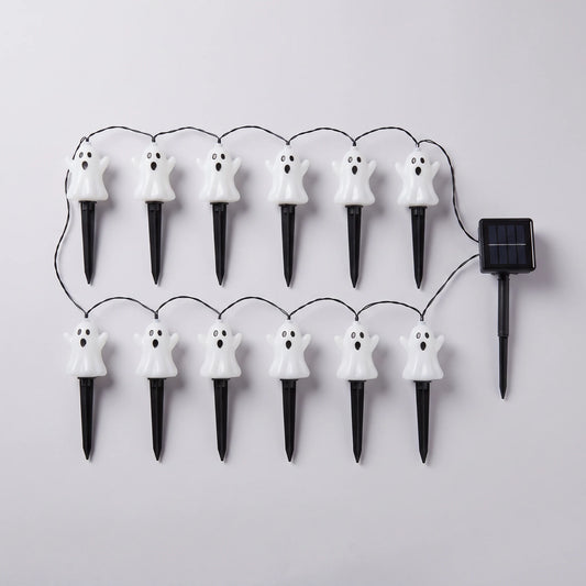 Twelve white ghost stake lights wired to a single solar panel, laid out flat on a pale grey background