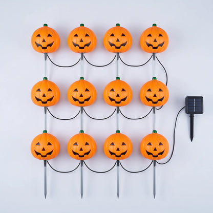 Twelve orange jack-o-lantern stake lights wired to a single solar panel, laid out flat on a pale background