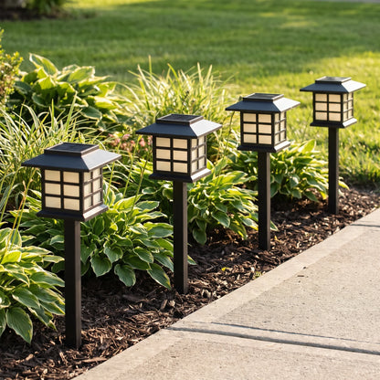 Solar lantern path lights edging a driveway flower bed in daylight