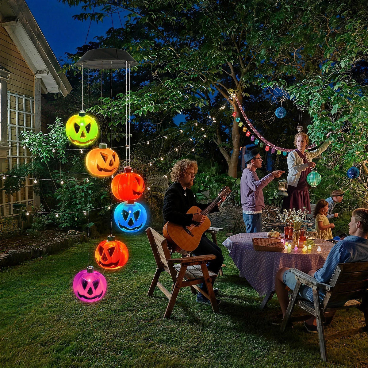Pumpkin wind chime hanging in a backyard at night during a Halloween party, its pumpkins lit in green, orange, red, blue and pink
