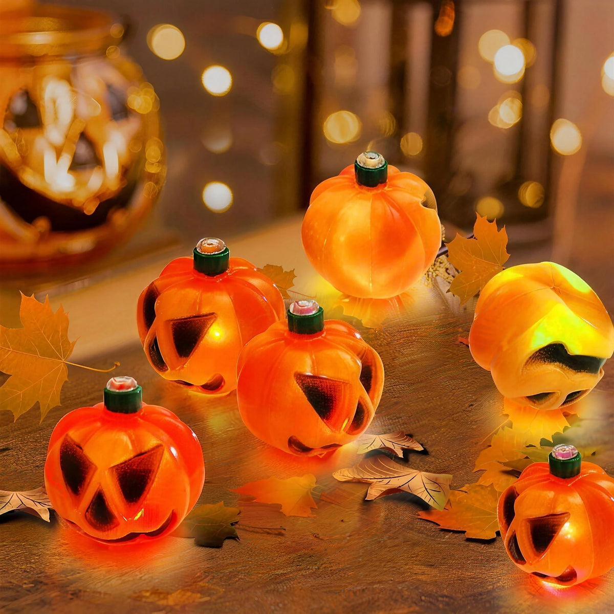 Close-up of the six lit jack-o'-lantern pumpkins on a wooden table with autumn leaves, each about 2.6 inches across