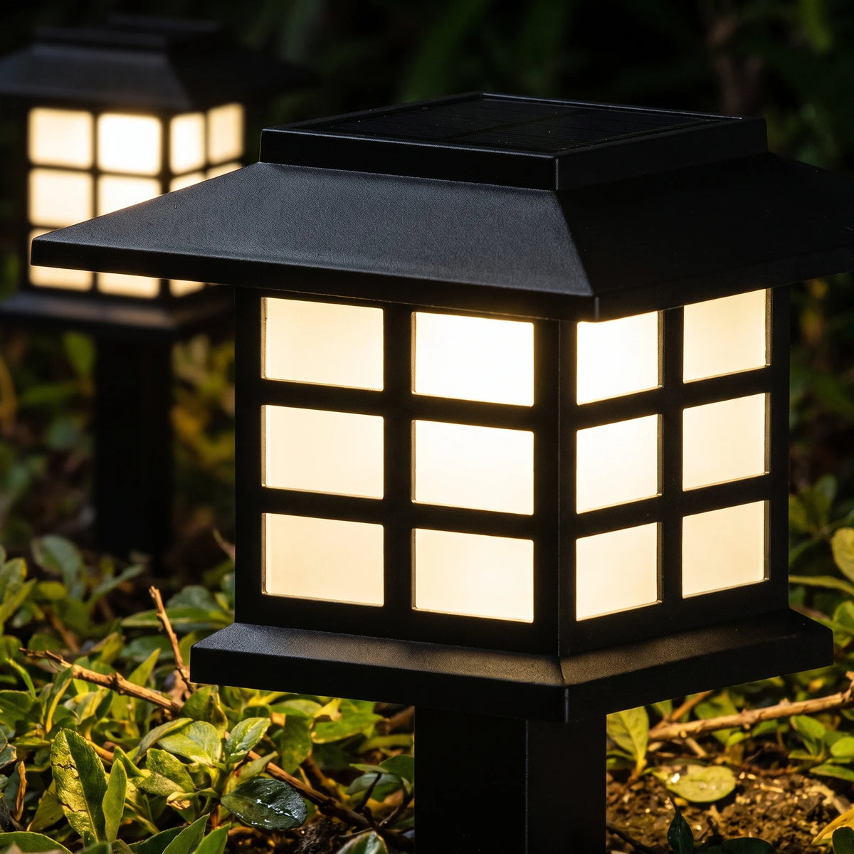 Close-up of a solar lantern path light glowing warm white at night