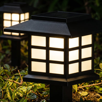 Close-up of a solar lantern path light glowing warm white at night