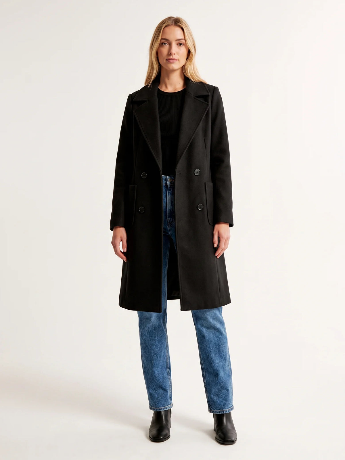 The Black wool-blend coat worn open on a model, photographed from the front in a studio