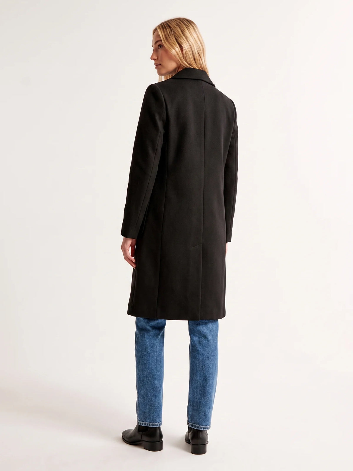 The back of the Black wool-blend coat on a model, showing the shoulder line and the below-the-knee hem