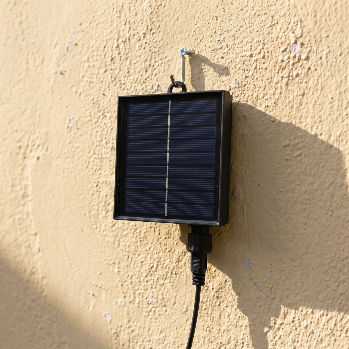 The solar panel hung on a screw hook on a garden wall