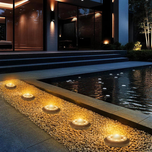 Solar ground lights set into pebbles beside a modern poolside patio at night